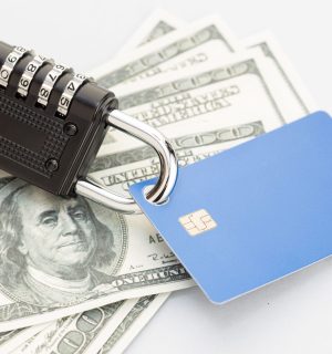 A Combination lock securing a stack of US dollar bills and a blue credit card, symbolizing financial security.